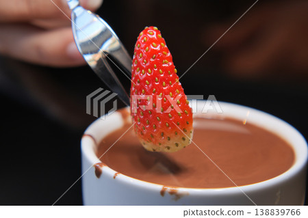 Dipping a strawberry in warm chocolate sauce 138839766