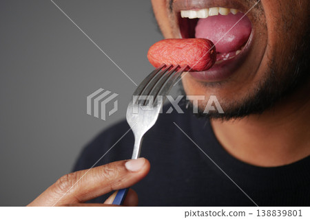 Close-Up Man Eating Sausage On Fork Showing Mouth, Tongue And Hand 138839801