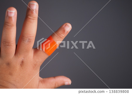 Injured finger with an orange bandage on a hand 138839808