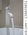 Water flowing from a faucet into a white basin 138839852