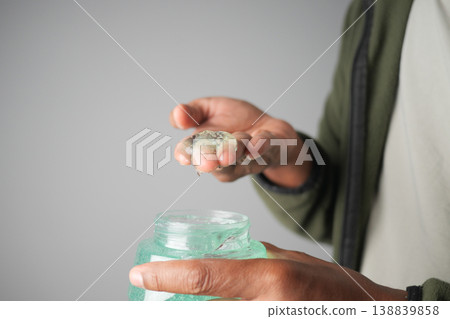 Man holds hair gel from jar in hands during personal care routine 138839858