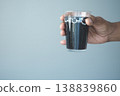 A hand holds a clear glass filled with soft drinks. 138839860