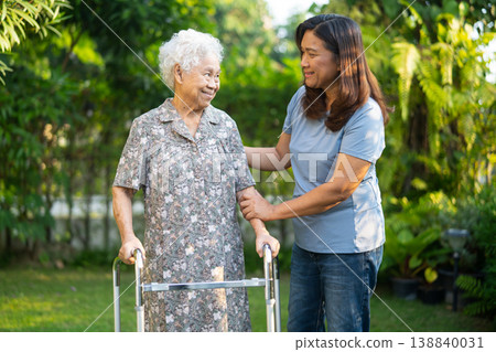 Caregiver help Asian elderly woman patient walk with walker in park. Caregiver help Asian elderly woman patient walk with walker in park. 138840031