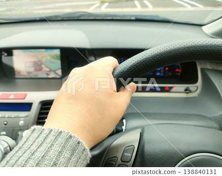 The hands of a driver gripping the steering wheel and driving a car 138840131