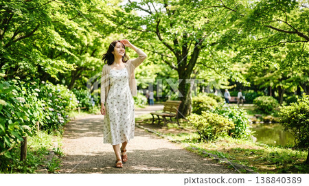 A refreshing woman walking through a park surrounded by fresh greenery. A refreshing woman walking through a park surrounded by fresh greenery. 138840389