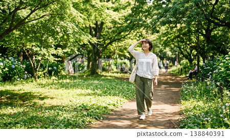 A refreshing woman walking through a park surrounded by fresh greenery. 138840391