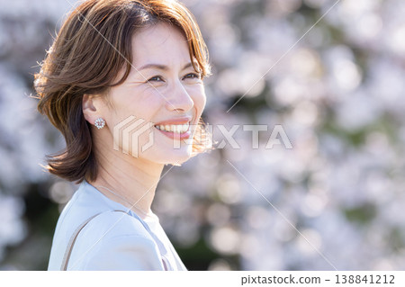 A middle-aged woman with cherry blossoms in the background A middle-aged woman with cherry blossoms in the background 138841212