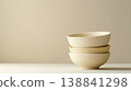 一張極簡主義靜物攝影作品，畫面中堆疊的陶瓷碗映襯在像牙色背景上。 138841298