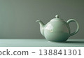 一張優雅的靜物照片，照片中一個陶瓷茶壺擺放在鼠尾草綠色的背景前。 138841301