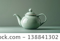 一張優雅的靜物照片，照片中一個陶瓷茶壺擺放在鼠尾草綠色的背景前。 138841302