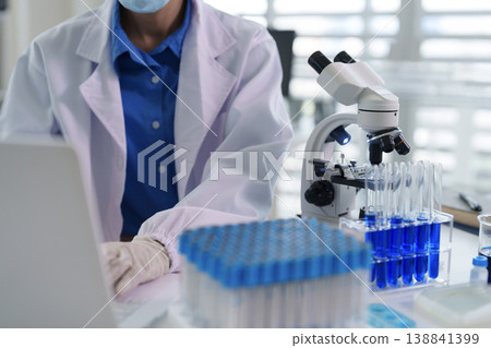 Adult Asian scientist researcher working laptop modern laboratory medical science experiment development microscope test tubes analysis data innovation 138841399