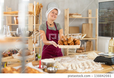 Young woman baker are standing near product range in bakery kitchen with basket of croissants. 138842081