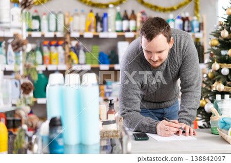 Middle-aged man restocking using paper in store with New Year decoration Middle-aged man restocking using paper in store with New Year decoration 138842097