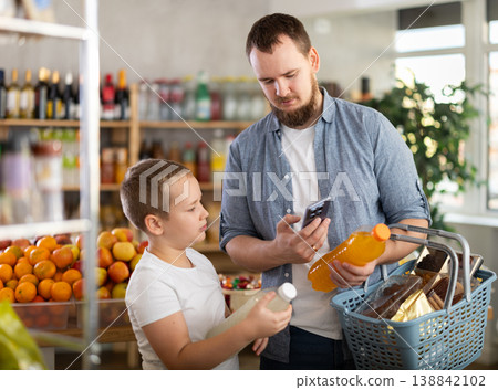 European man with son customer at shop scans QR code on drink bottle using phone camera 138842102