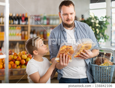 Father and preteen son choosing packaged cut poultry in grocery store Father and preteen son choosing packaged cut poultry in grocery store 138842106