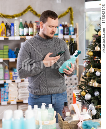 In Christmas decorated shop, man client scanning QR code on package paint remover In Christmas decorated shop, man client scanning QR code on package paint remover 138842108