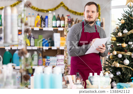 Male salesman makes notes on paper - keeps track of the receipt and expenditure of goods in supermarket 138842112