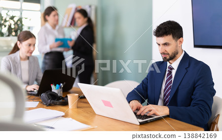 Young man works on laptop with colleagues Young man works on laptop with colleagues 138842169