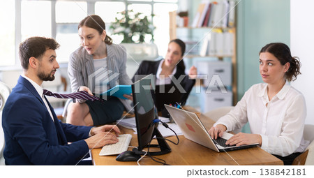 Young woman flirting with male colleague while sitting on office desk Young woman flirting with male colleague while sitting on office desk 138842181
