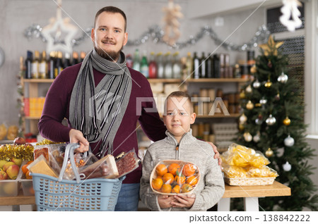 Father and son standing in festive market with chosen products in hands 138842222