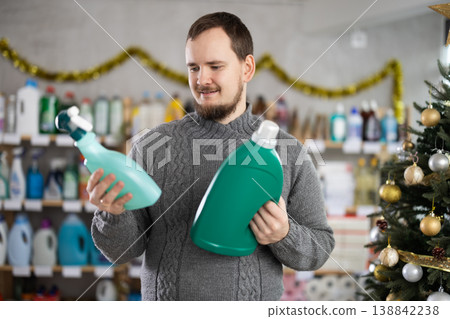 Bearded man customer buying spray and detergent in store decorated for New Year holiday 138842238