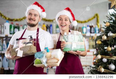 Cheerful sellers in Santa hats offering cleaning supplies and toiletries in store 138842296
