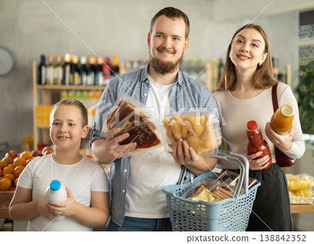 Preteen boy shopping for groceries together with parents at store Preteen boy shopping for groceries together with parents at store 138842352