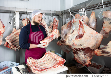 Bearded butchery worker preparing fresh veal cuts for sale Bearded butchery worker preparing fresh veal cuts for sale 138842356