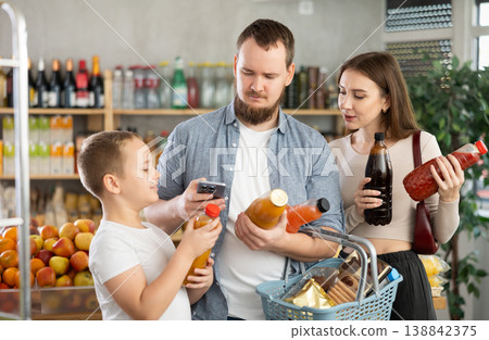 Family scanning barcodes on juice bottles in grocery store Family scanning barcodes on juice bottles in grocery store 138842375