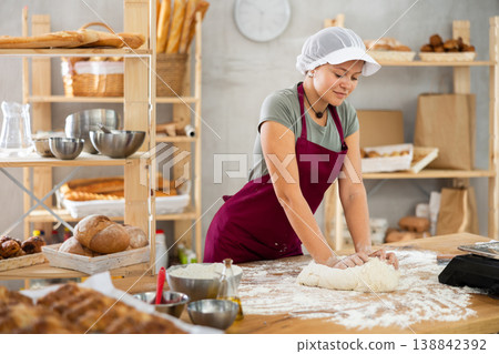 Woman works in bakery as baker, kneads dough, works with flour. Woman works in bakery as baker, kneads dough, works with flour. 138842392
