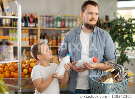 Young man with tween son choosing organic bottled milk in store Young man with tween son choosing organic bottled milk in store 138842393