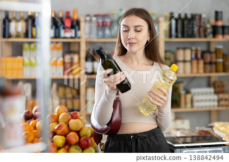 Woman chooses vegetable oil or olive oil while shopping in grocery supermarket Woman chooses vegetable oil or olive oil while shopping in grocery supermarket 138842494