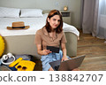A happy young woman buys tickets on her laptop. Preparing for vacation, planning a trip.  138842707