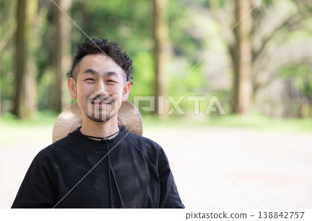 A smiling Japanese man looking directly at the camera, portraying an image of outdoor leisure and outings in a lush, green outdoor campsite. A smiling Japanese man looking directly at the camera, portraying an image of outdoor leisure and outings in a lush, green outdoor campsite. 138842757