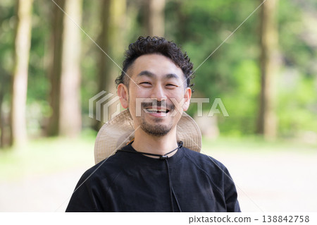 一位微笑的日本男子直視鏡頭，展現了在鬱鬱蔥蔥的戶外露營地進行戶外休閒和郊遊的景象。 138842758
