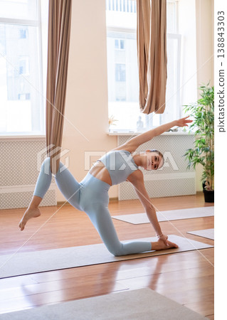 Gymnastics balance. Stretching exercise. Young woman bending for body health stability with fly yoga hammock support in sport center. 138843303