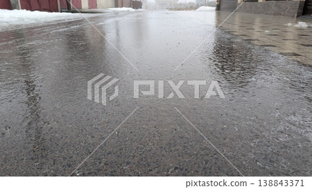 Damp asphalt reveals dull overcast sky and building shadows Damp asphalt reveals dull overcast sky and building shadows 138843371