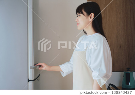 A woman opens a refrigerator and checks its contents. Scenes from daily life and meal preparation. 138843427