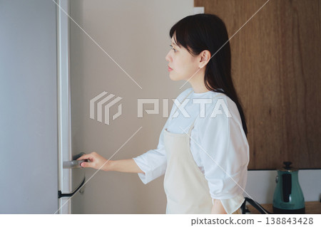 A woman opens a refrigerator and checks its contents. Scenes from daily life and meal preparation. 138843428