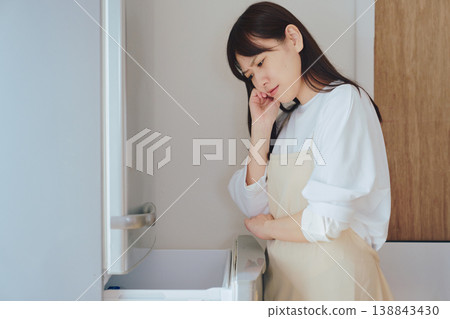 一位女士正在翻看冰箱,為缺少食材或難以決定做什麼菜而煩惱——這是日常生活中常見的景象。 一位女士正在翻看冰箱,為缺少食材或難以決定做什麼菜而煩惱——這是日常生活中常見的景象。 138843430