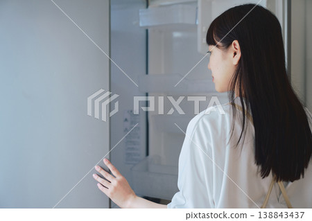 一位女士打開冰箱,檢視裡面的東西。日常生活和備餐場景。 一位女士打開冰箱,檢視裡面的東西。日常生活和備餐場景。 138843437