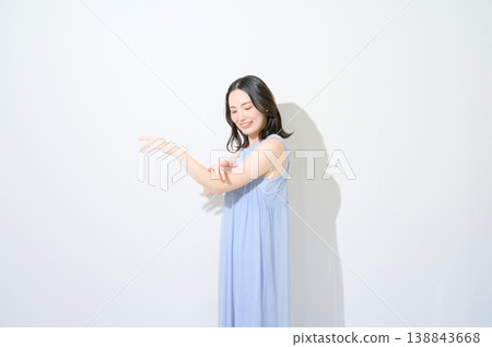一張美麗的日本女性照片，她正在白色背景上的手臂上塗抹防曬霜。 138843668