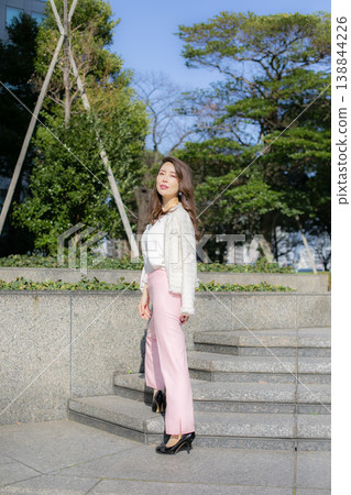 A young, tall woman strolling through a park in spring. A young, tall woman strolling through a park in spring. 138844226