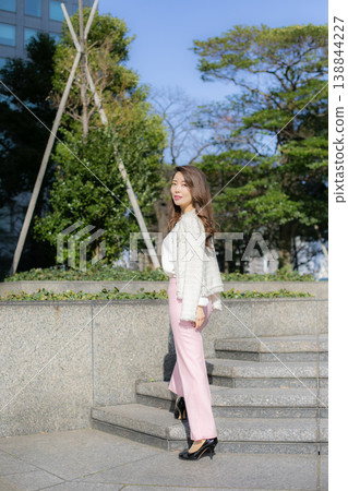 A young, tall woman strolling through a park in spring. A young, tall woman strolling through a park in spring. 138844227