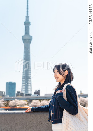 A woman smiling with the Tokyo Skytree in the background, along the Sumida River. (Sightseeing/Travel) A woman smiling with the Tokyo Skytree in the background, along the Sumida River. (Sightseeing/Travel) 138844438