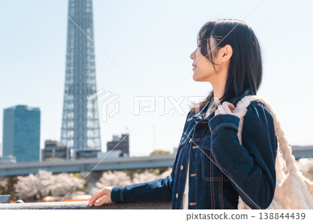 A woman smiling with the Tokyo Skytree in the background, along the Sumida River. (Sightseeing/Travel) A woman smiling with the Tokyo Skytree in the background, along the Sumida River. (Sightseeing/Travel) 138844439
