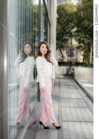 A young woman standing in the daytime city skyline. A young woman standing in the daytime city skyline. 138844468