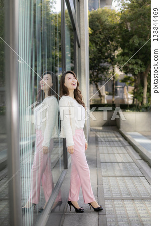 A young woman standing in the daytime city skyline. 138844469
