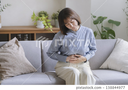 一位年近五十的女子摀著肚子。 138844977