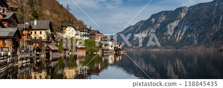Panoramic view of alpine lake with mountain reflections, Hallstatt and dramatic cliffs in Austria Panoramic view of alpine lake with mountain reflections, Hallstatt and dramatic cliffs in Austria 138845435